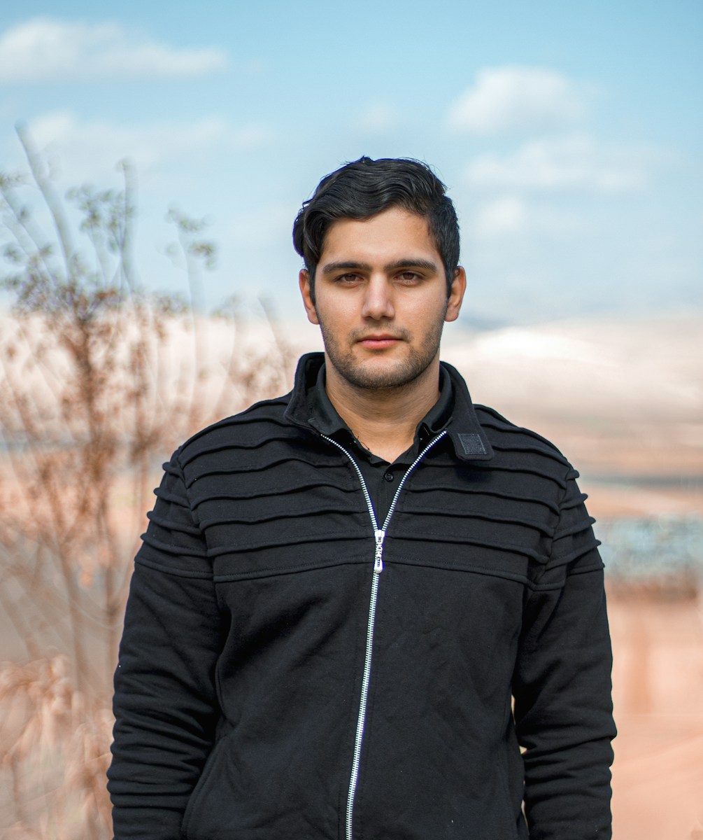 man in black zip up jacket standing on brown field during daytime